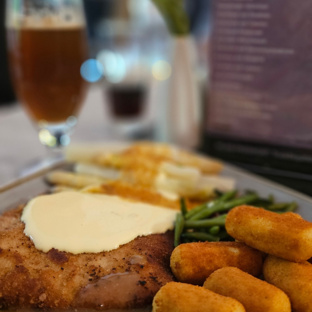 Zu sehen ist ein Teller mti Schnitzel, Kroketten und Spargel. 