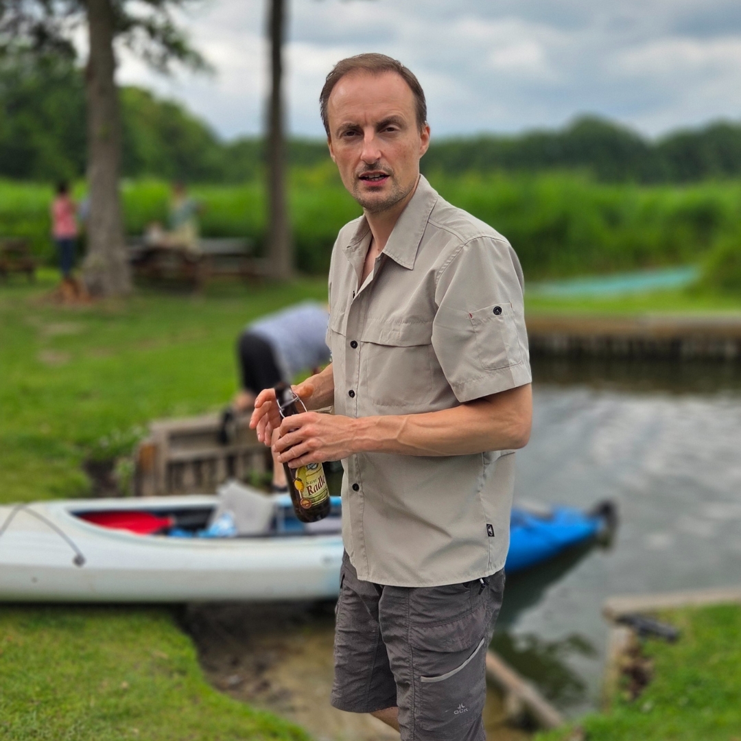 Zu sehen ist eine Person mit einer Getränkeflasche in der Hand. Im Hintergrund erkennt man einen Kajak