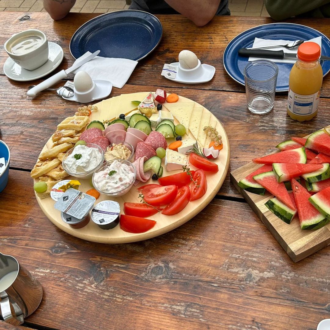 Zu erkennen sind eine Snackplatte, mehrere Stücke Wassermelone sowie ein gedeckter Tisch.
