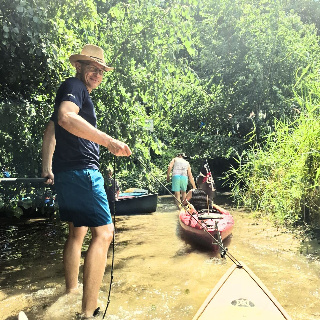 Zu sehen sind zwei Personen die im Wasser stehen und ihre Kajaks hinterher ziehen