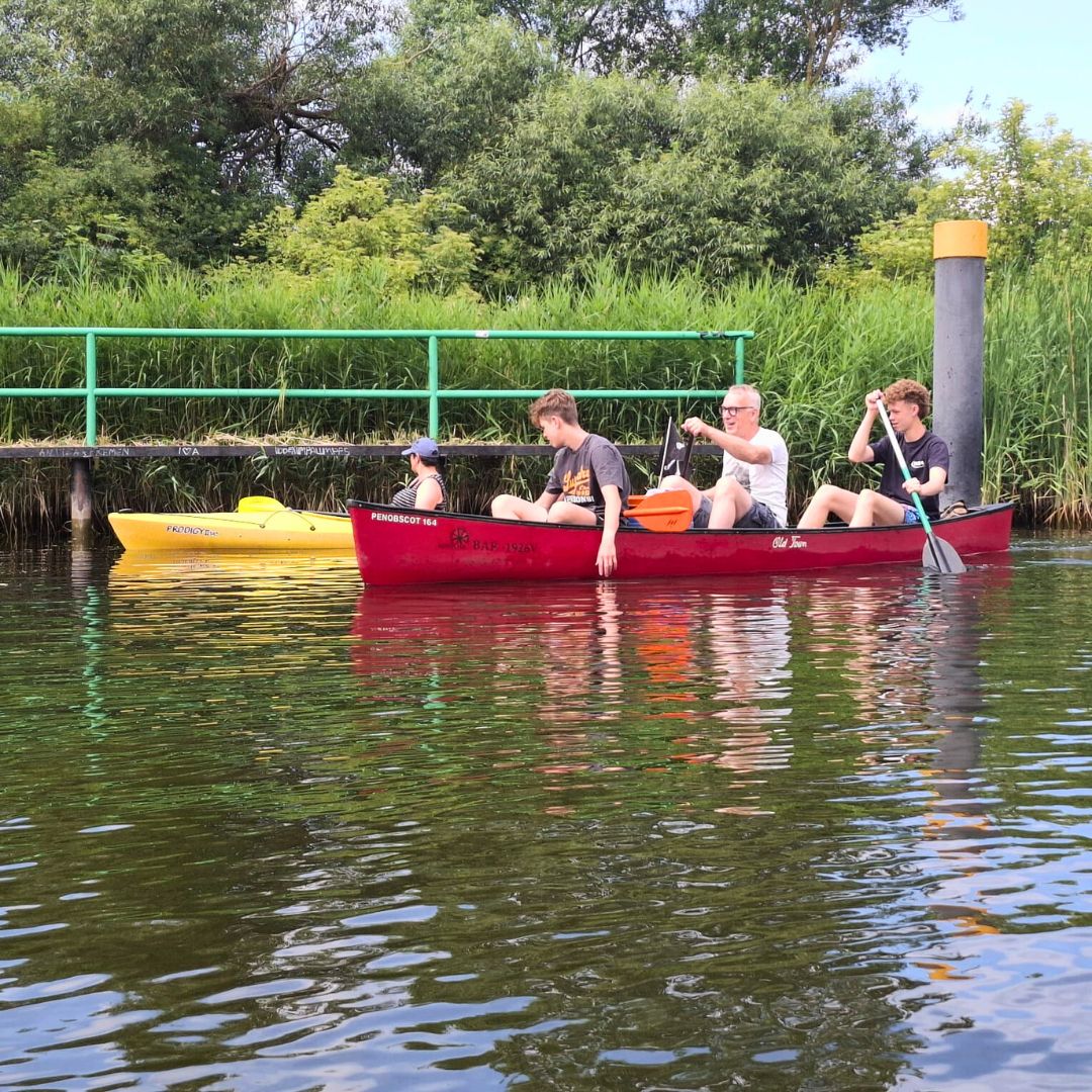Zu sehen sind drei Personen in einem roten Kajak schwimmend im Wasser
