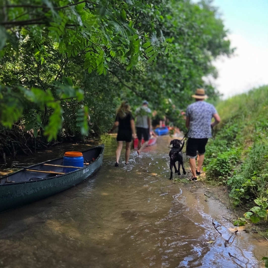 Zu sehen sind zwei Personen die im Wasser stehen und ihre Kajaks hinterher ziehen